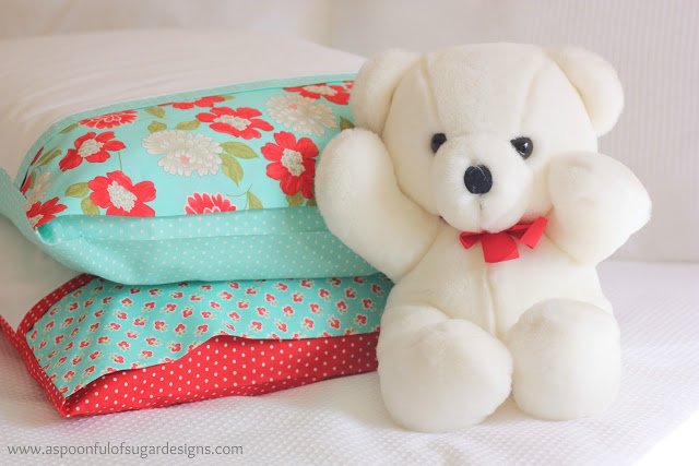 white teddy bear next to two pillows