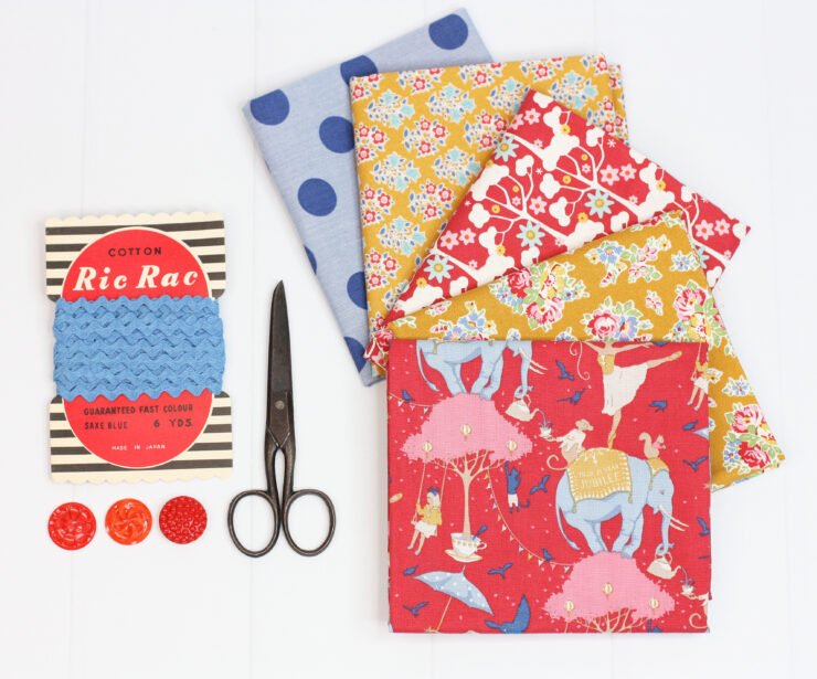 bundle of fabrics fanned out. Scissors and vintage ricrac next to fabric.