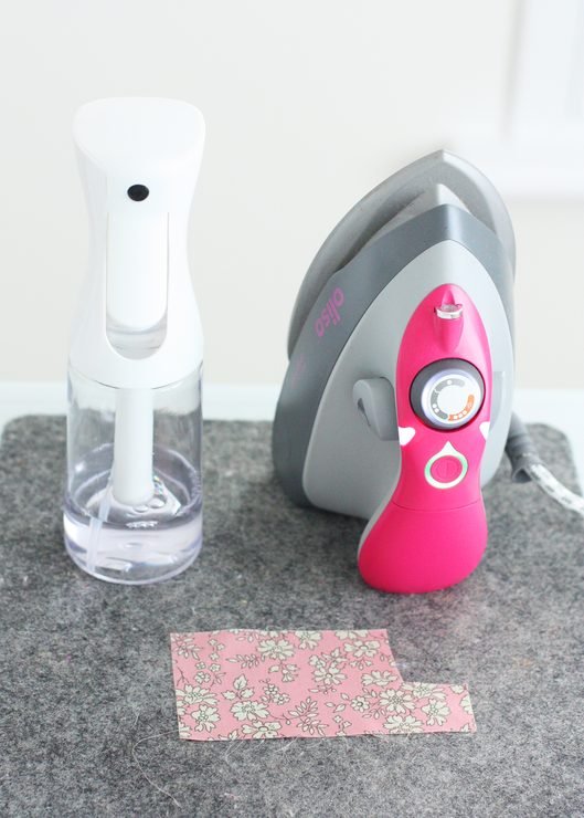 Pink iron and sprayer on a grey felt mat