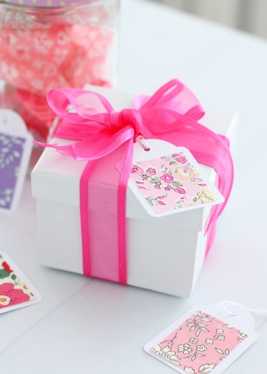 a gift wrapped in a pink bow with fabric gift tag