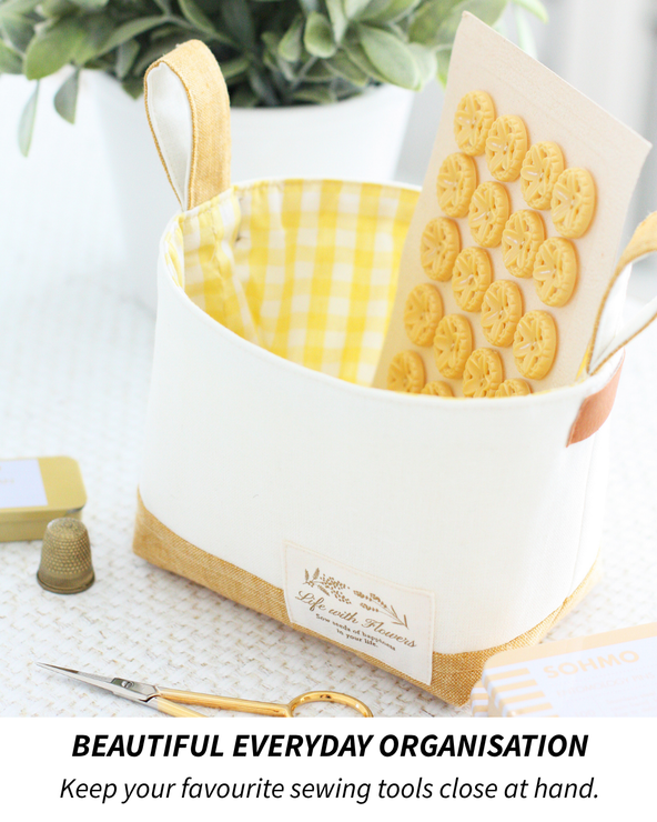 Luma Bucket sewing pattern filled with sewing notions including buttons, scissors, pins, and a thimble for organized craft storage.