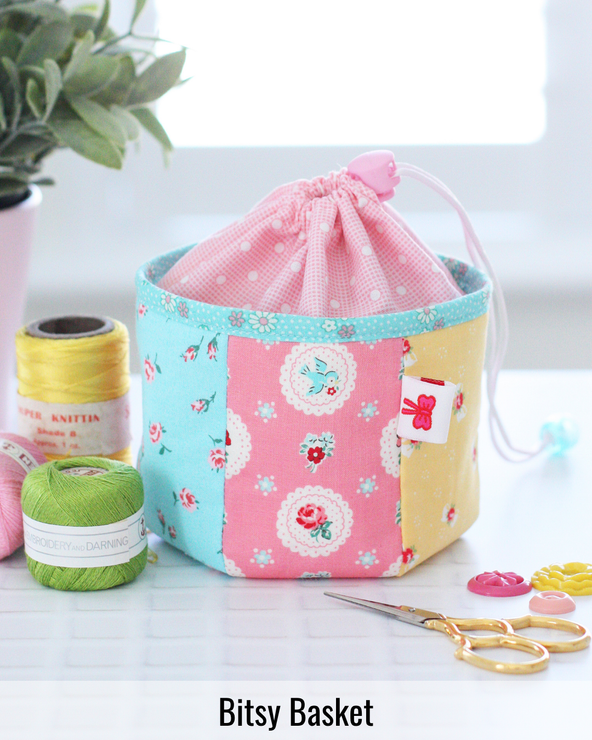 Small fabric Bitsy Basket filled with sewing supplies and notions, ideal for organizing clips, thread, and sewing accessories.